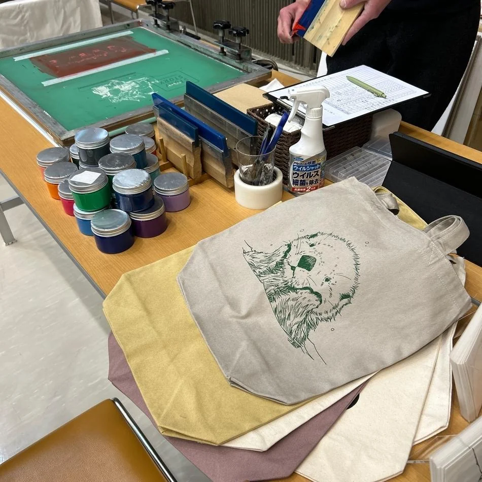 Canvas tote bags beside a screen printing workbench